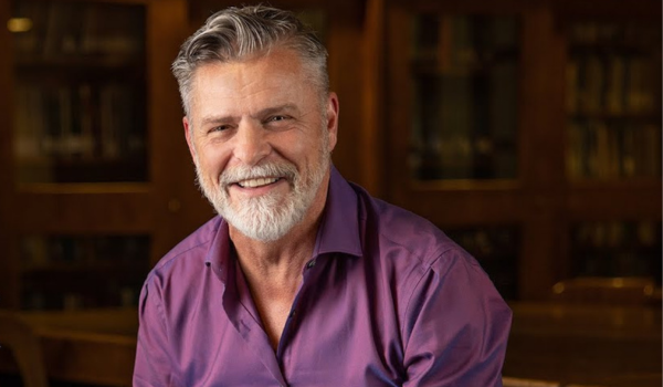 A portrait of Joel Faflak in an appropriately warm and bookish setting