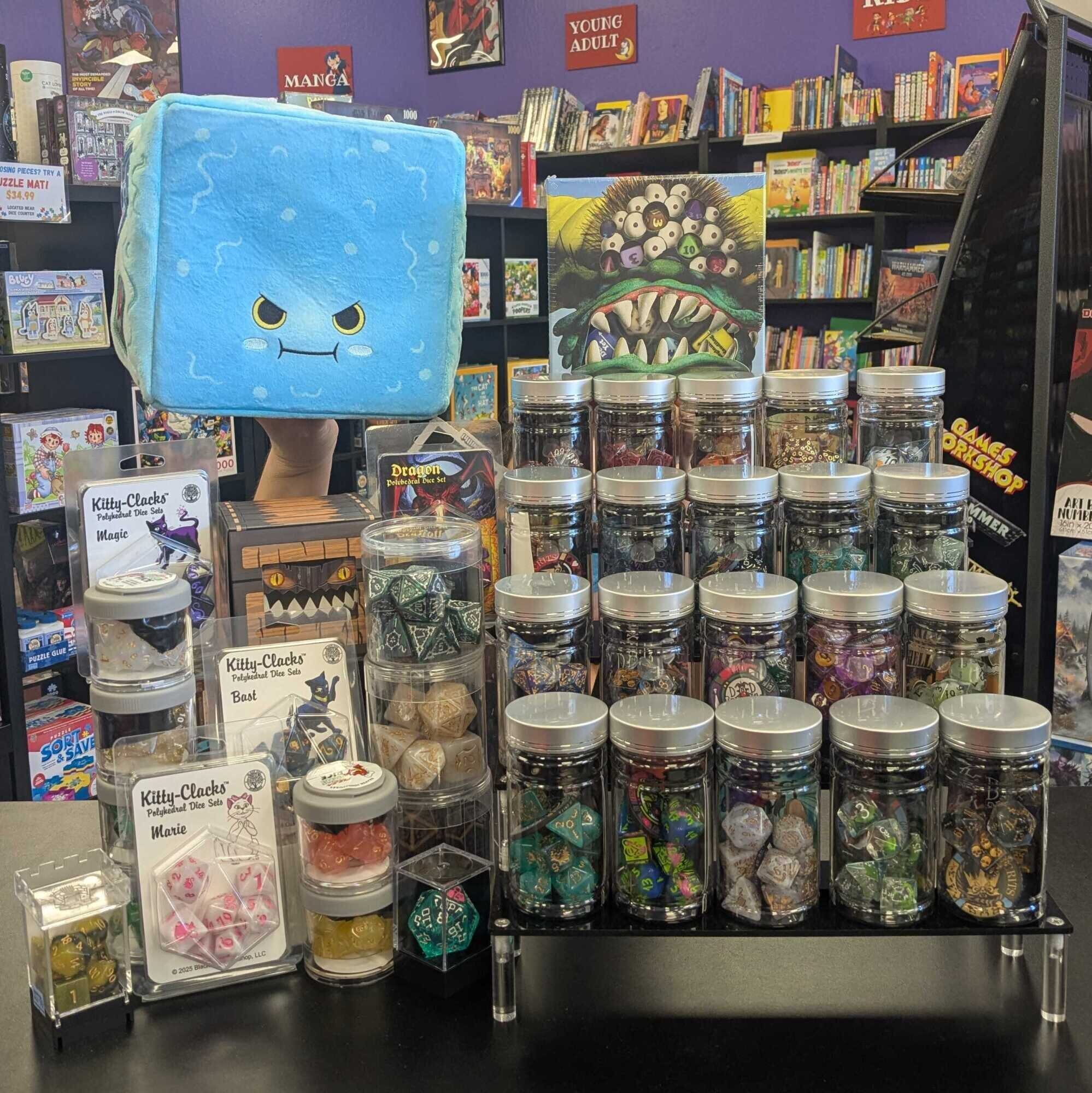 Display of various rpg dice sets with a plushie gelatinous cube looking over them.