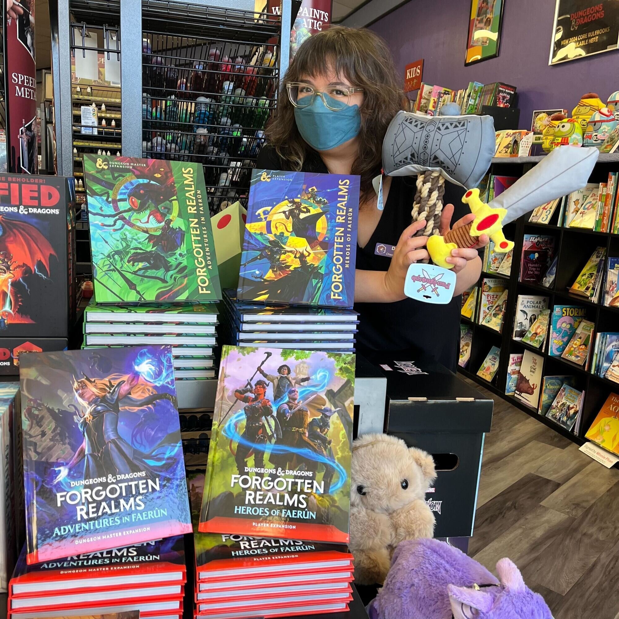 Danae showing off D&D pet toys next to new Faerun D&D books