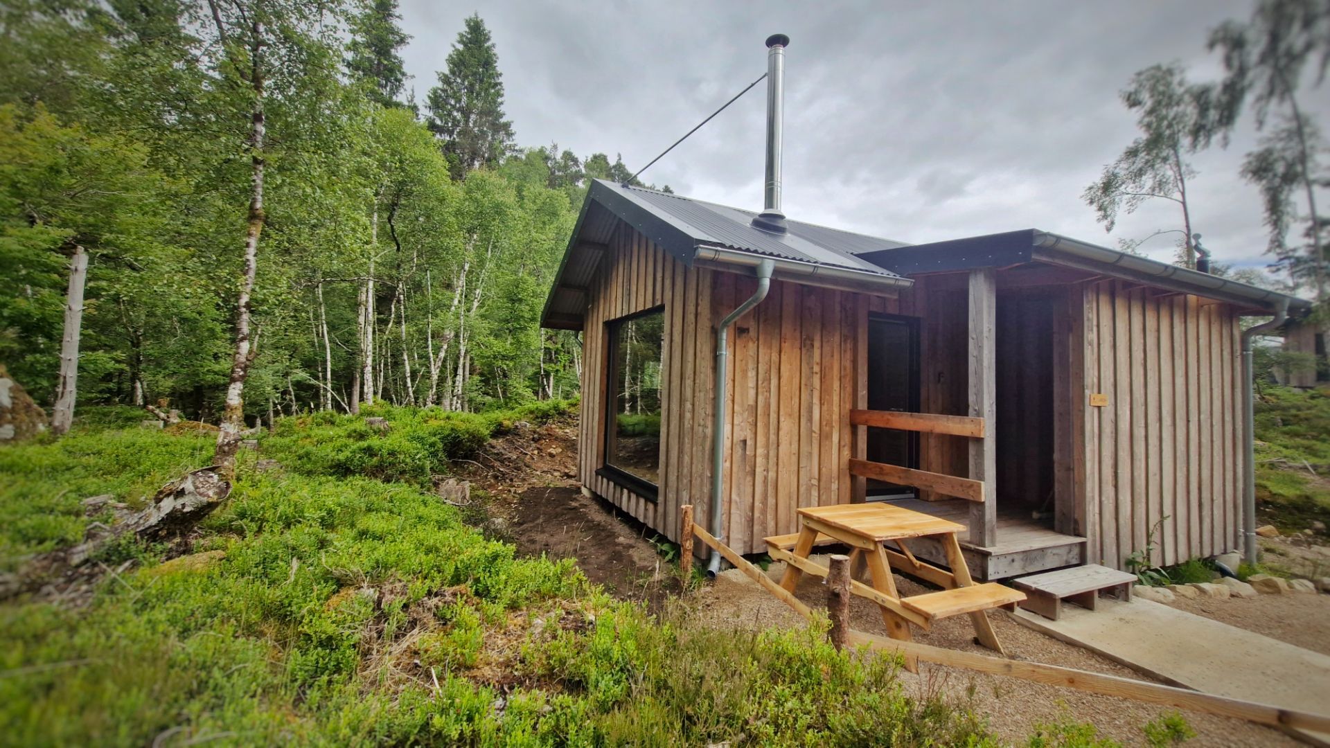 Birch cabin with one of Andy's picnic benches beside it.