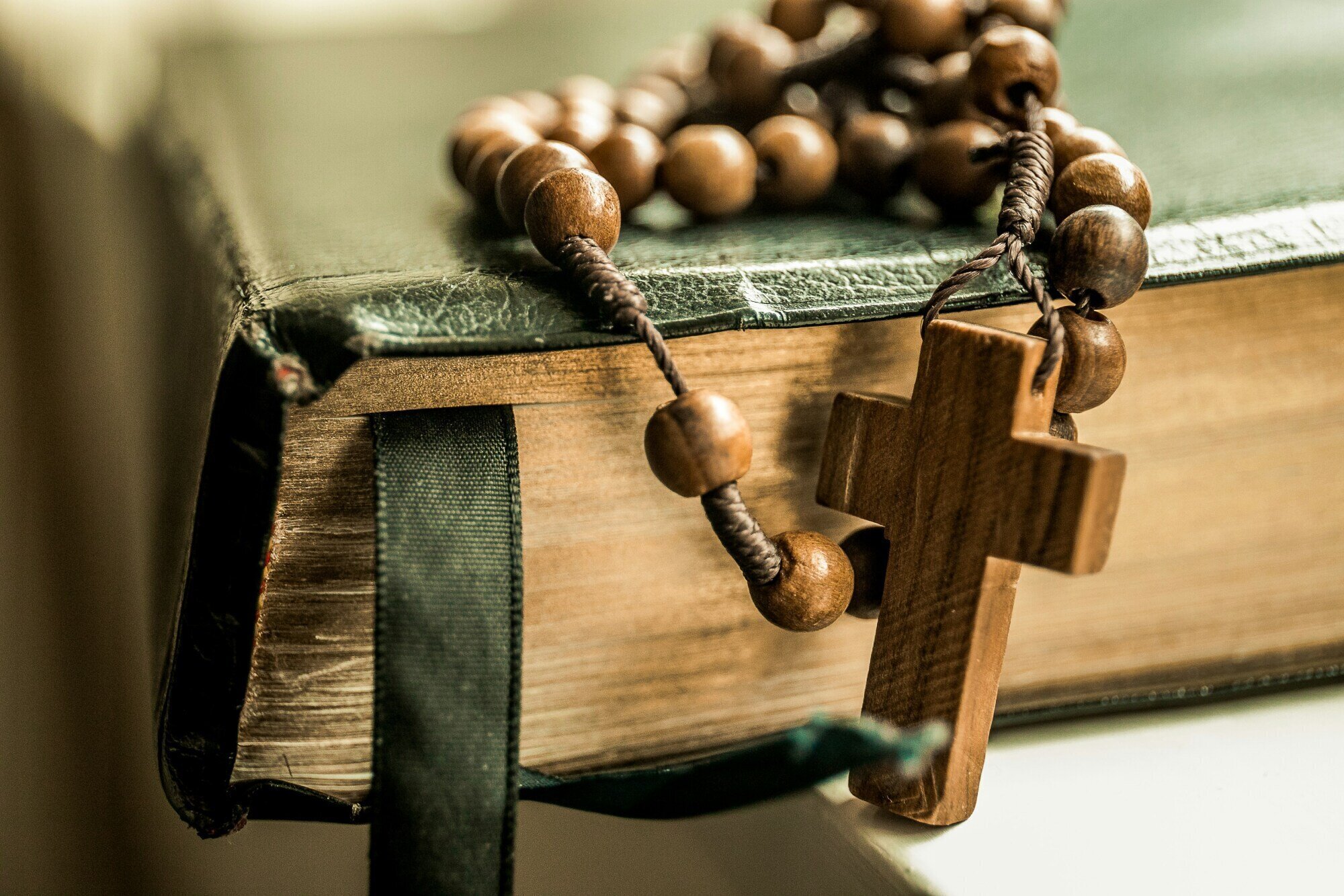Rosary with wooden beads on top of a closed leather-bound book