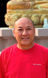 New director, Ugyen Shola in front of our Maitreya statue