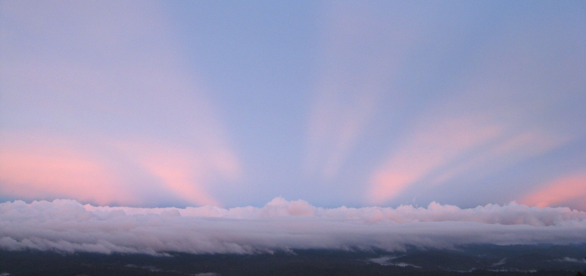 pink and blue sunrise colors streaming from behind the clouds 