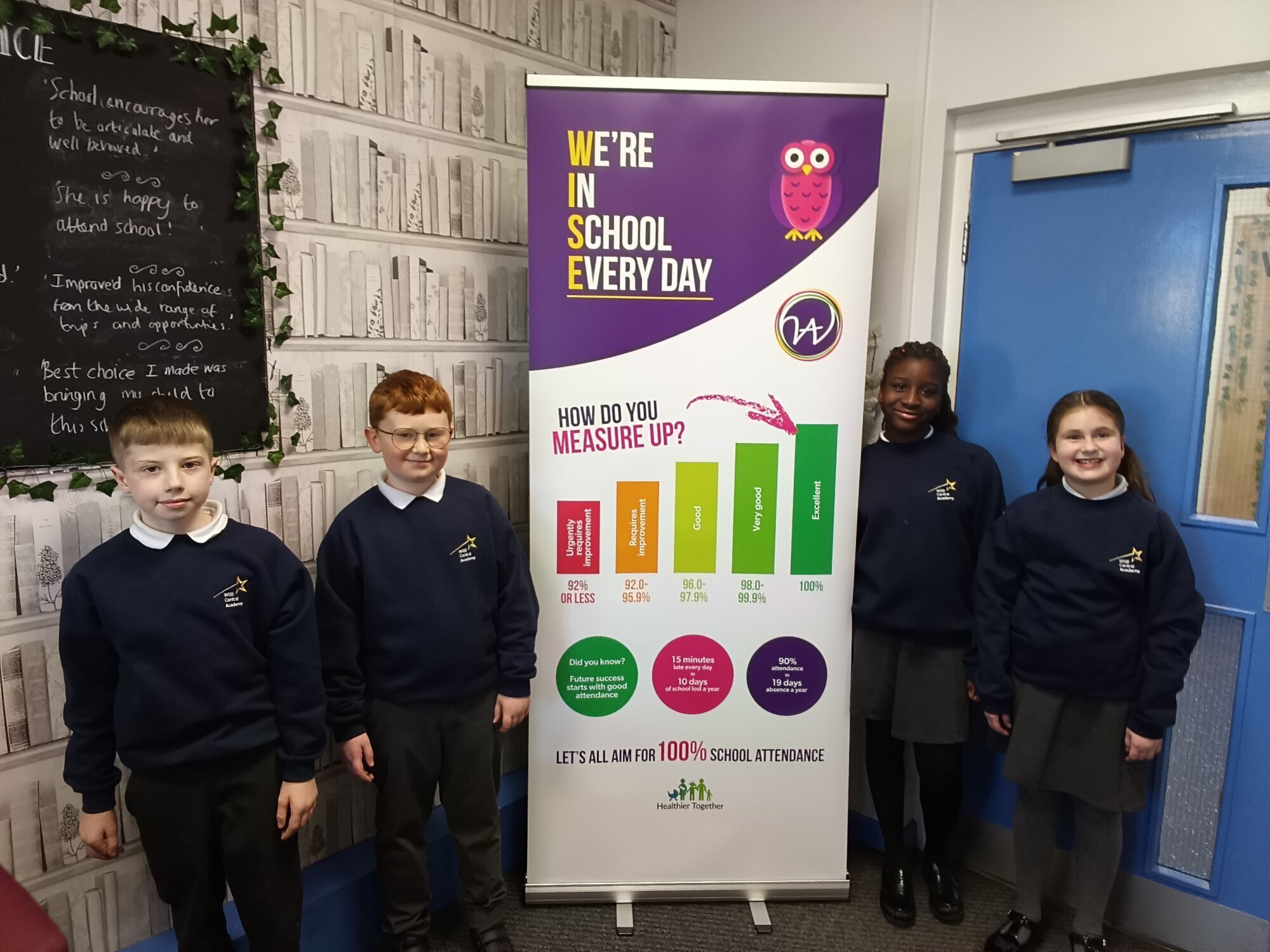 Children wearing their new Bothal Academy jumpers in front of the new school welcome sign