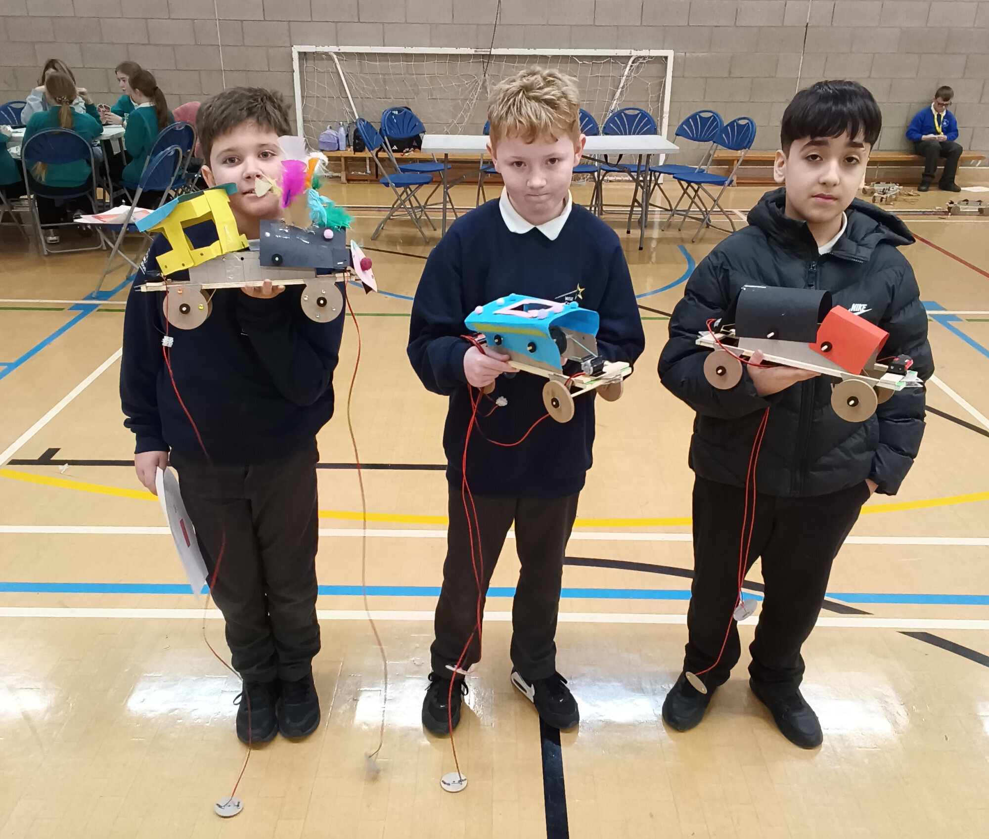 Three boys from Central Academy with their electric-powered train models at the Primary Engineer event in Killingworth.