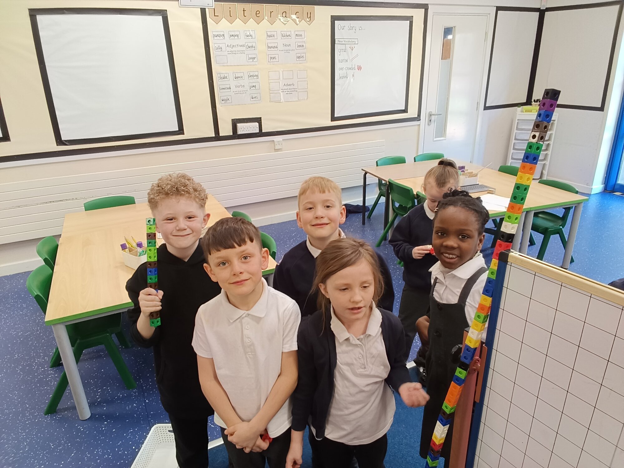Six children with a tower of blocks taller than the whiteboard